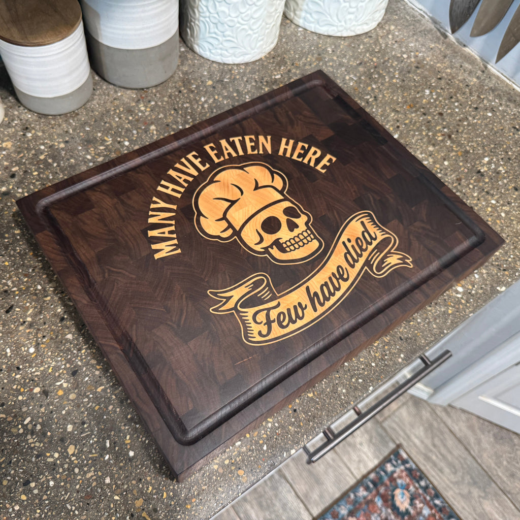 cutting board with skull and chef hat design on a concrete counter top in a kitchen