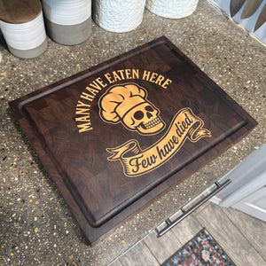 cutting board with skull and chef hat design on a concrete counter top in a kitchen
