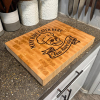 Wooden cutting board with skull design and text on a kitchen counter.