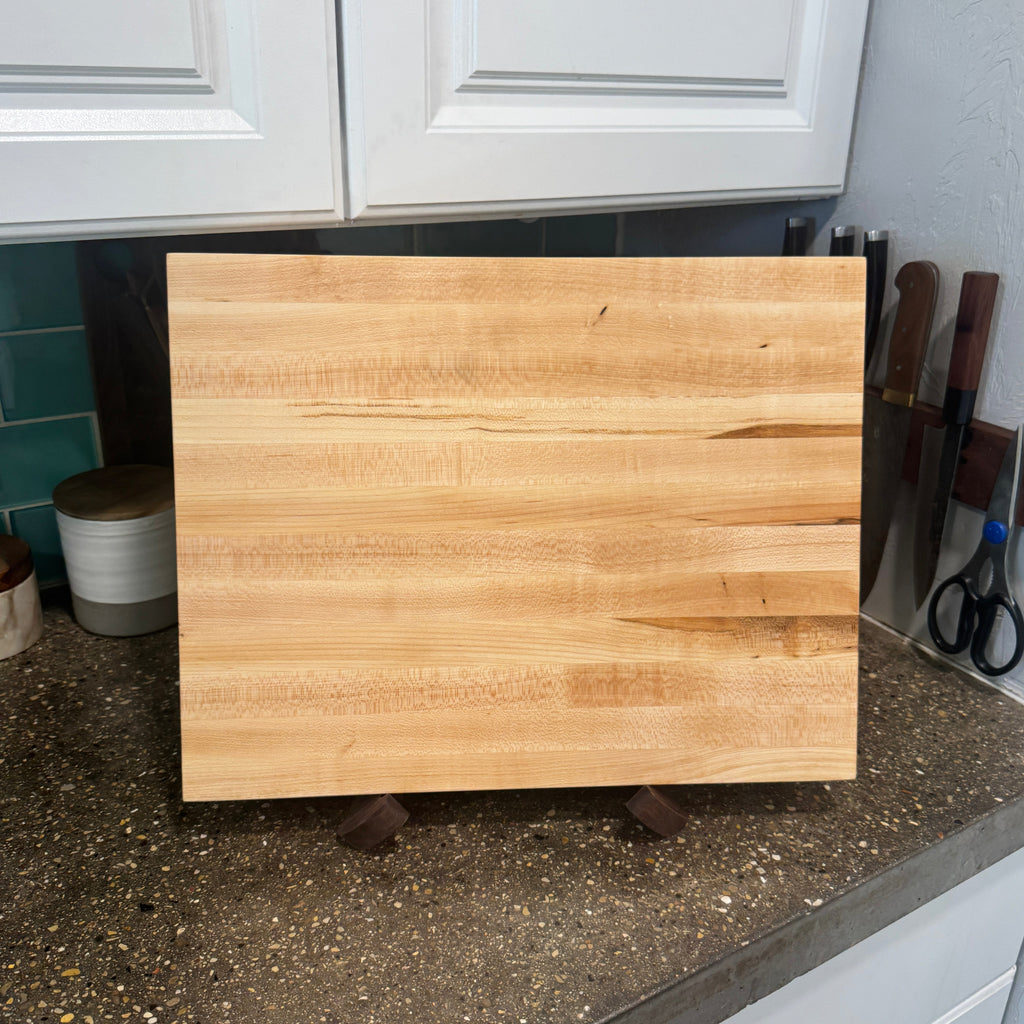 Wooden cutting board on a kitchen counter with cabinets in the background.