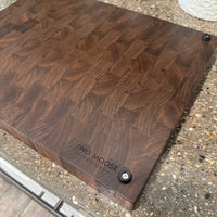 Wooden cutting board with 'Two Moose' branding on a concrete surface