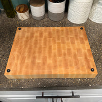 Wooden cutting board on a speckled kitchen countertop with decorative items.